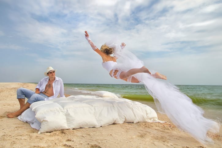 Woman jumping into bed with husband